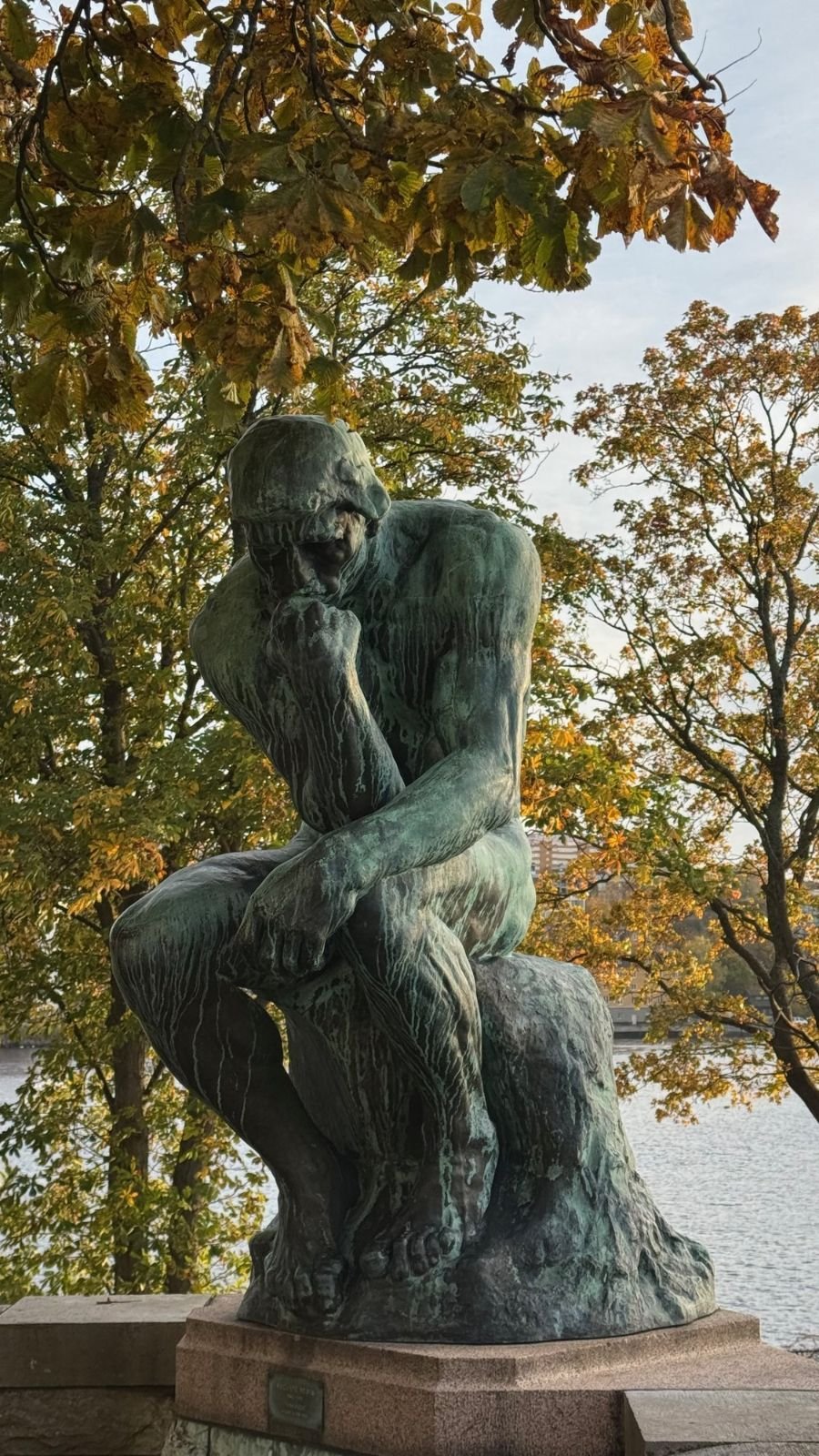 The bronze sculpture The Thinker by Rodin under autumn trees by the water at Waldemarsudde.