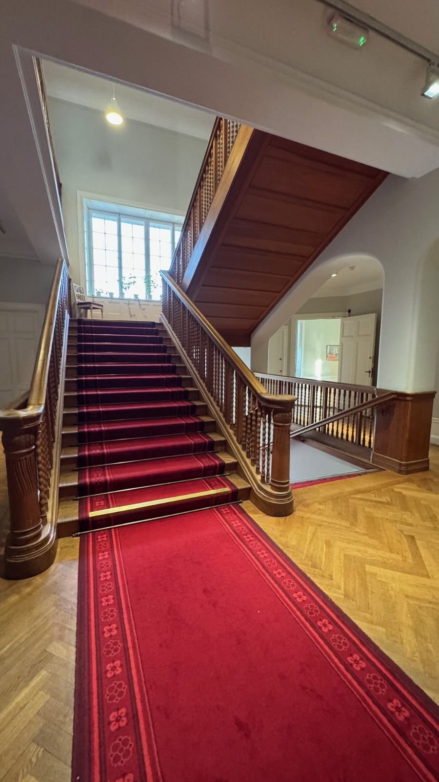 A wooden staircase with a red carpet in the Waldemarsudde mansion.