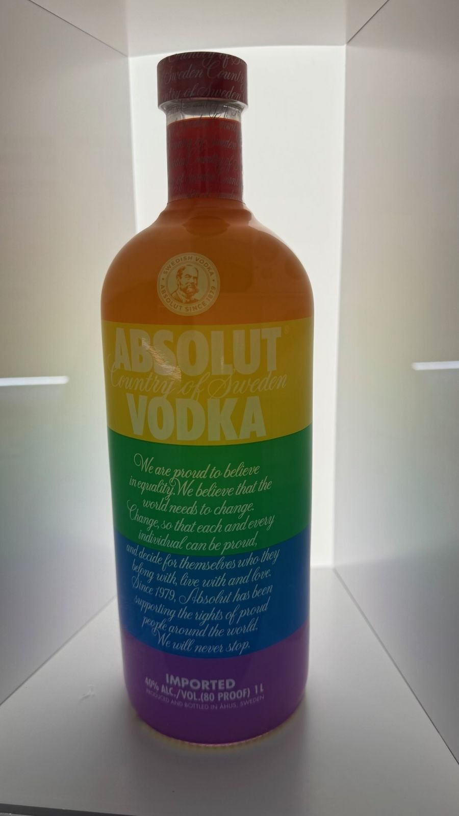 A limited edition Absolut Vodka bottle in rainbow colors in a lit glass case at Spritmuseum.