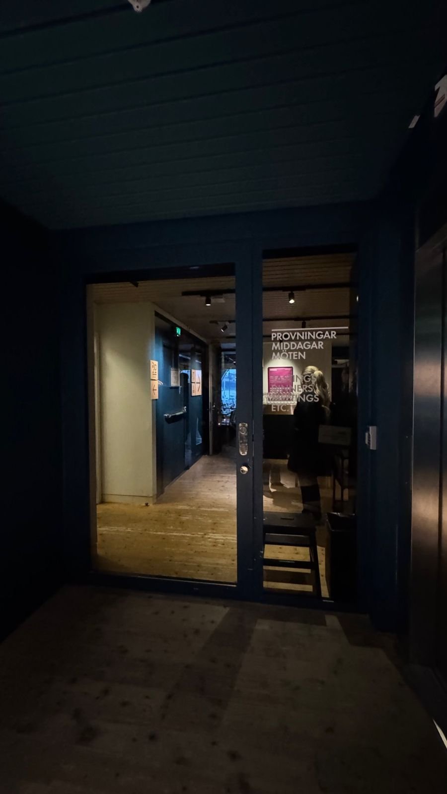 Open glass doors with a low threshold lead to a hall with a wooden floor at Spritmuseum.