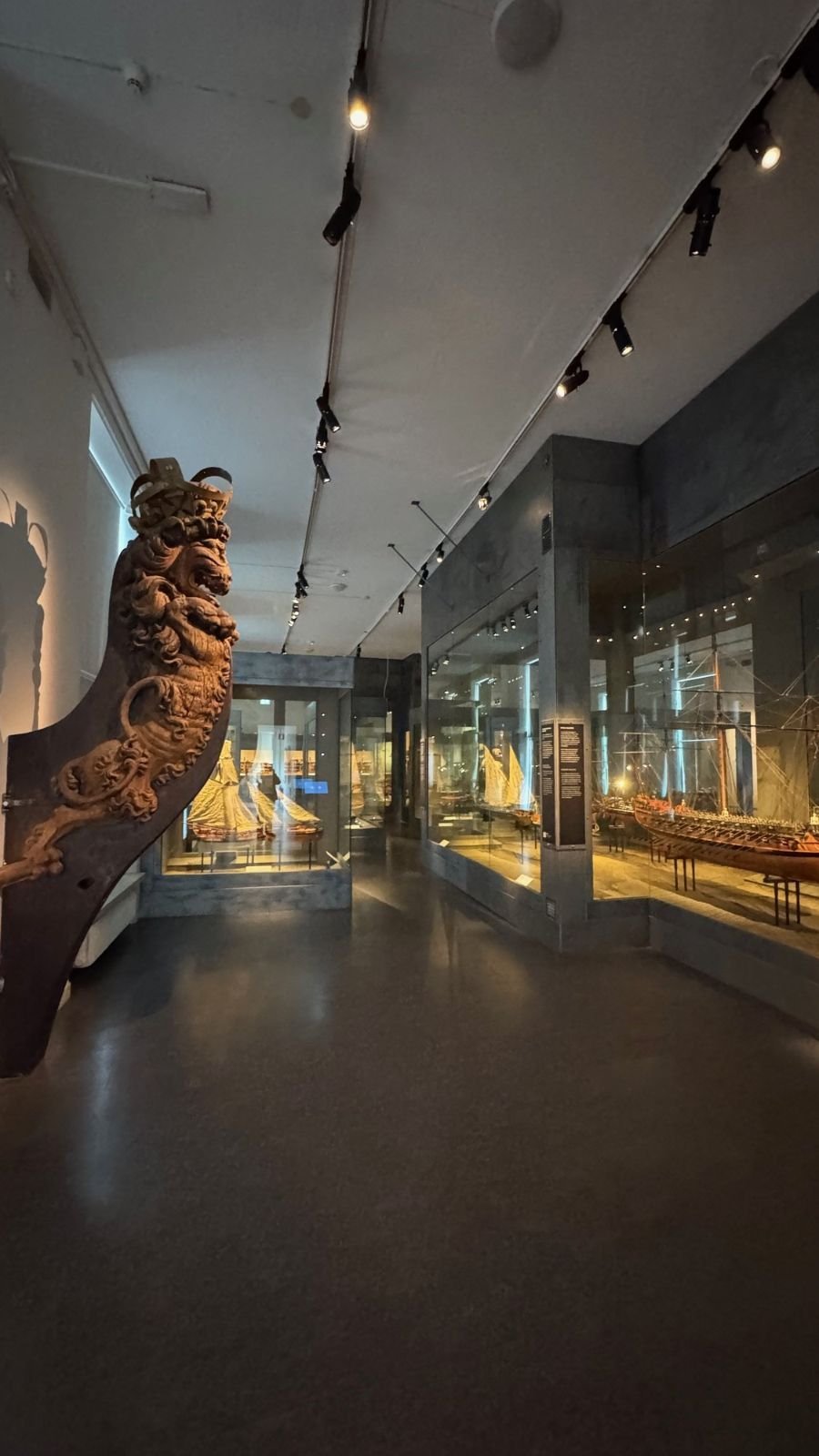 A carved wooden figurehead in a dark exhibition hall at Sjöhistoriska museet.