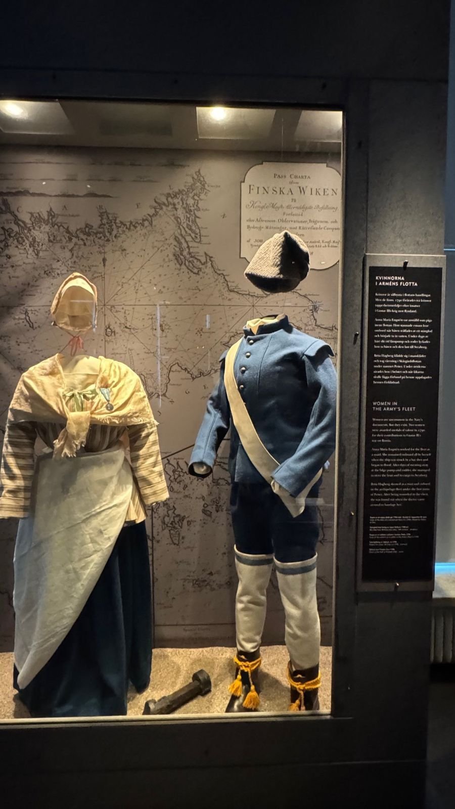 Historic sailor clothes on two figures in a glass case at Sjöhistoriska museet.