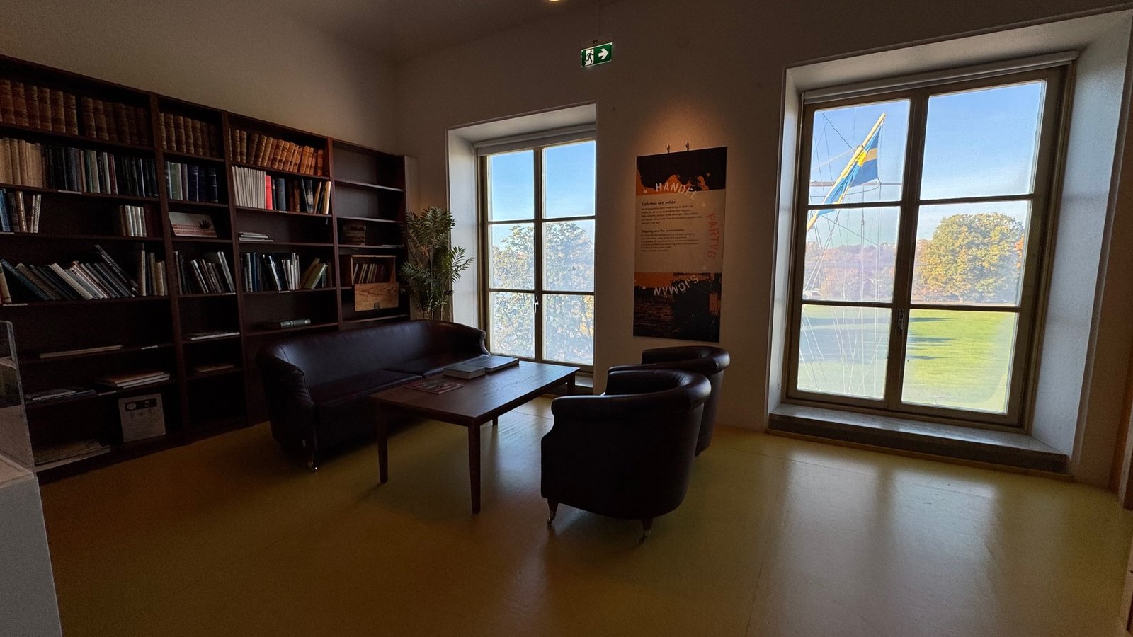 A reading room with bookshelves, leather chairs and tall windows at Sjöhistoriska museet.