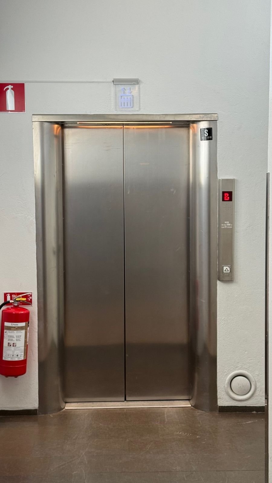 A steel lift door next to a fire extinguisher at Sjöhistoriska museet.