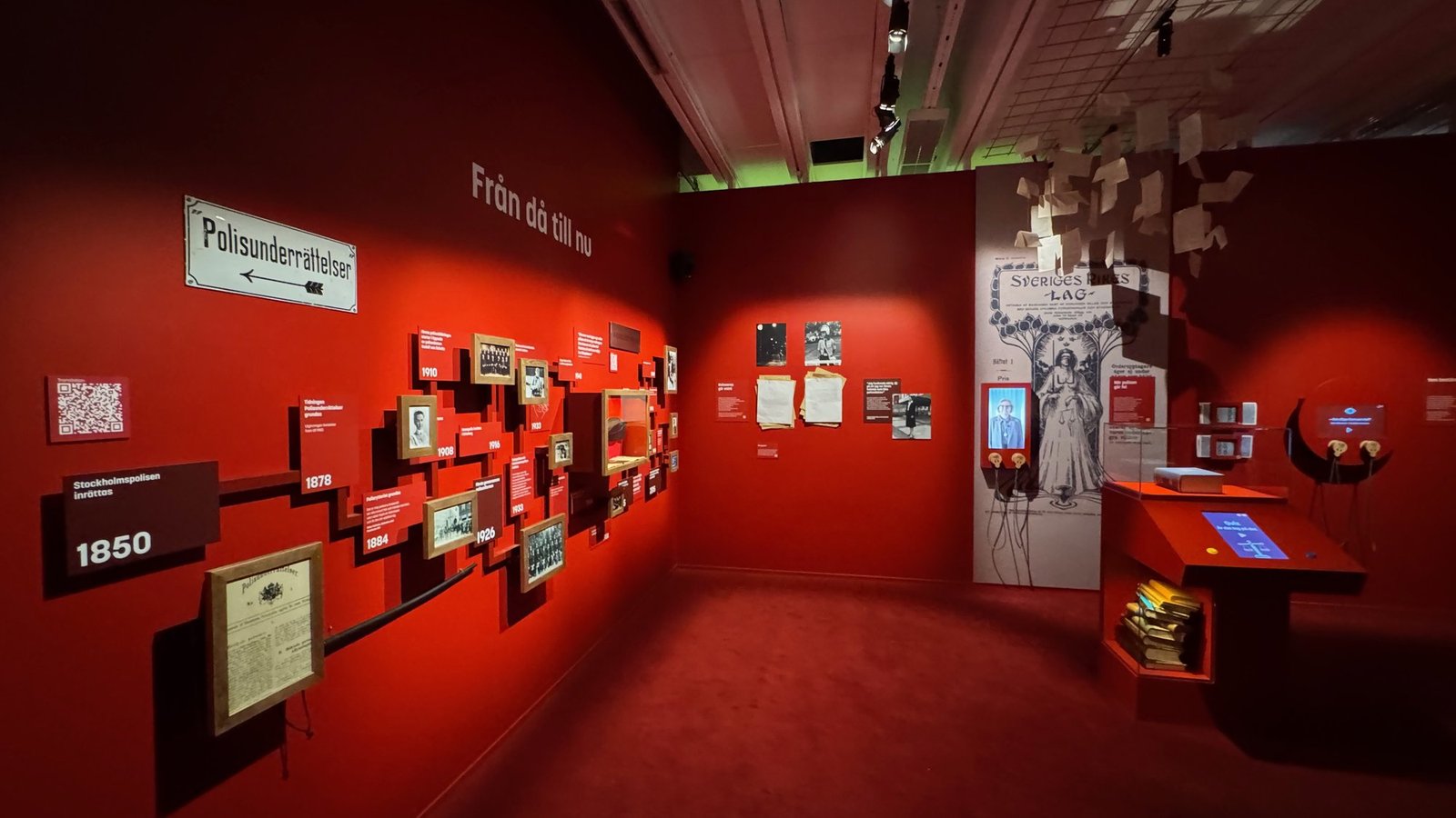 A red exhibition room with police history on the walls at Polismuseet.