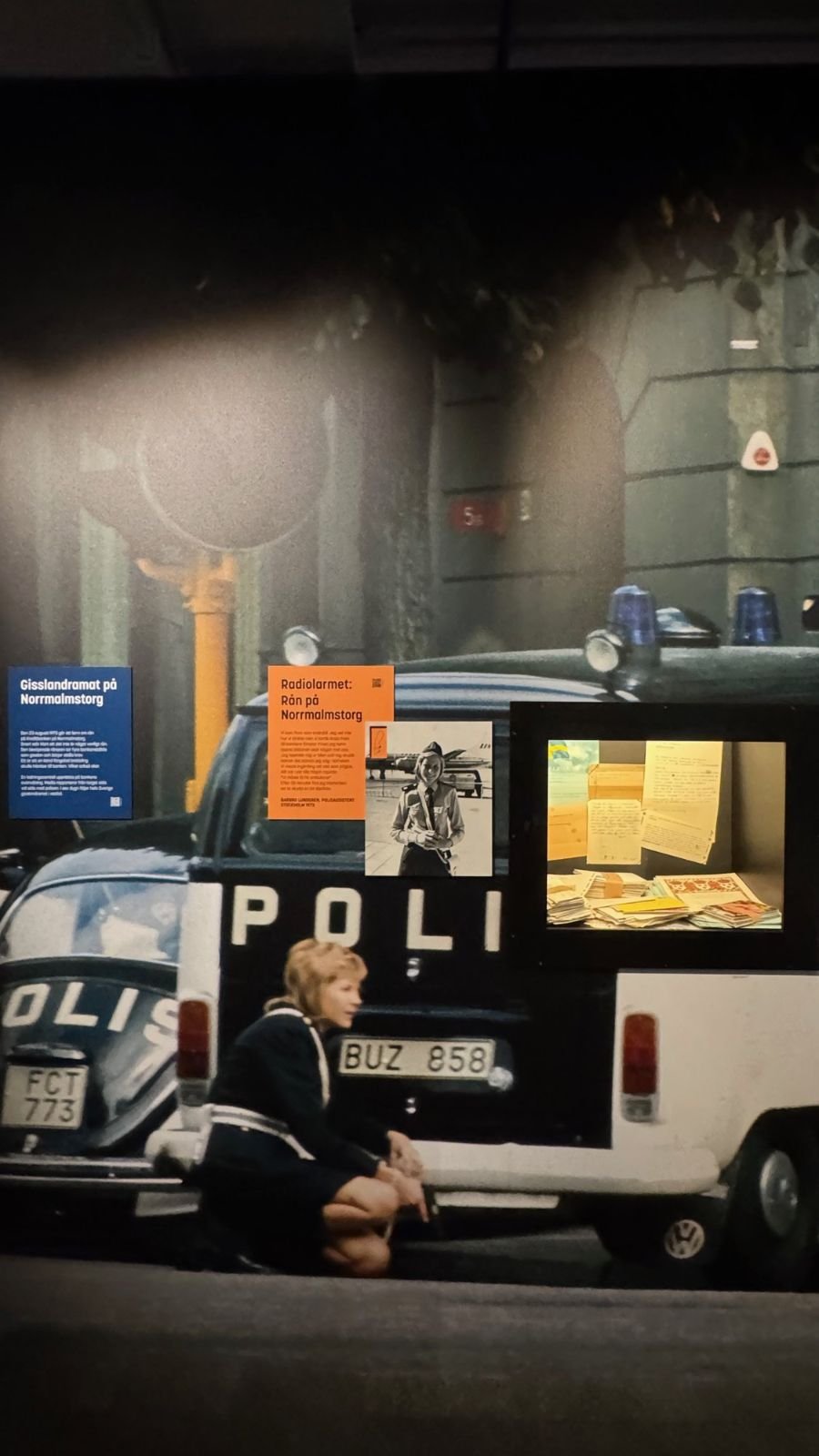 An old black and white police car with a large historic photo of a policewoman at Polismuseet.