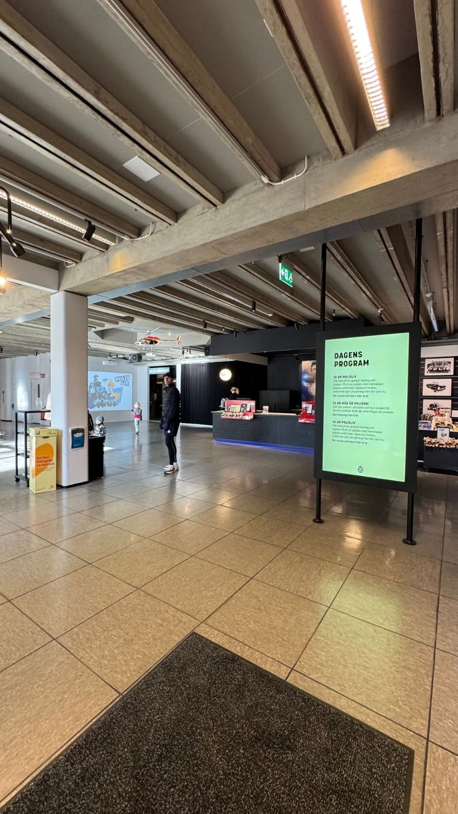 The wide entrance hall with a flat floor and an exhibition sign at Polismuseet.