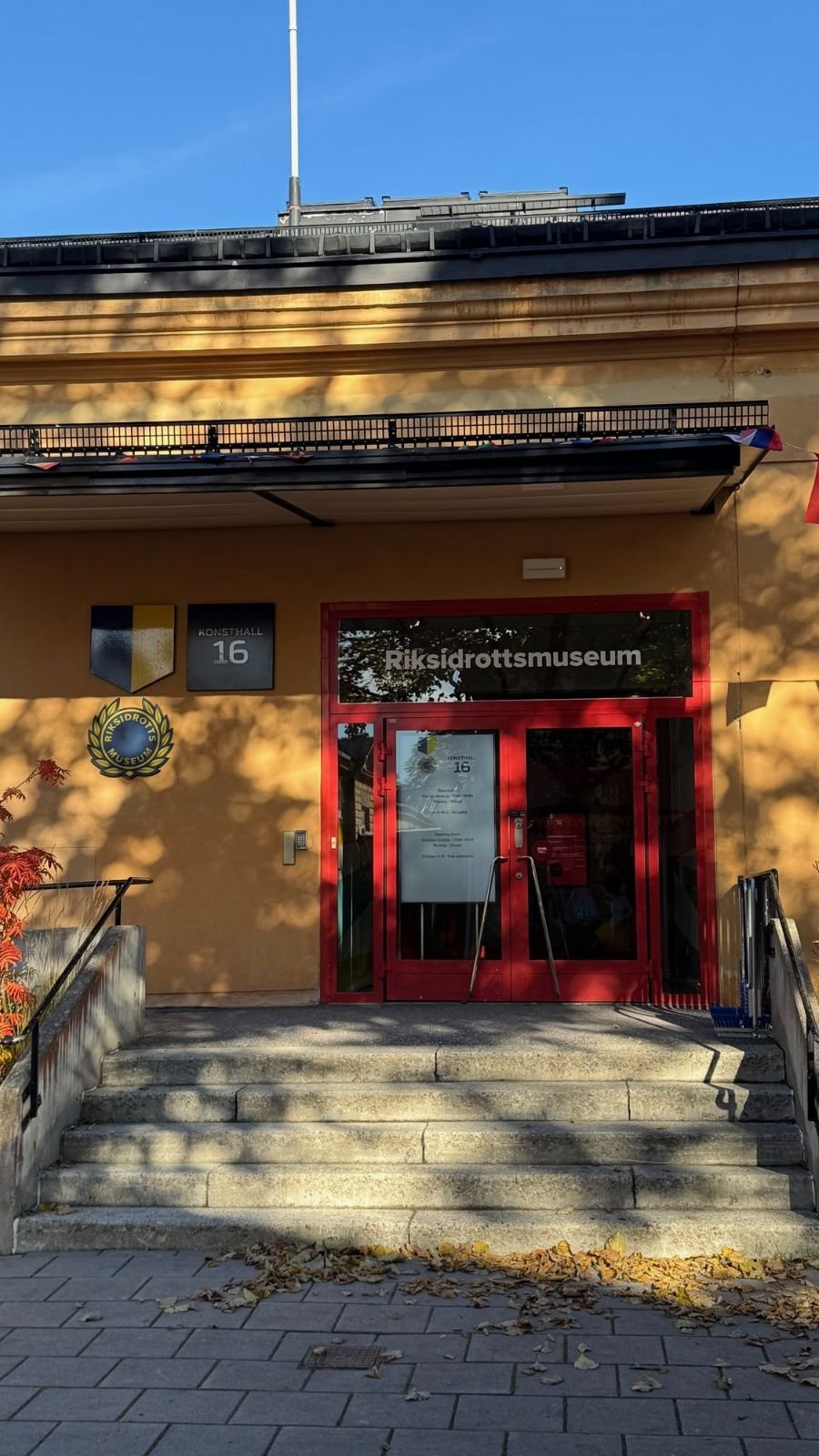 The entrance to Riksidrottsmuseet with red doors and short stairs.