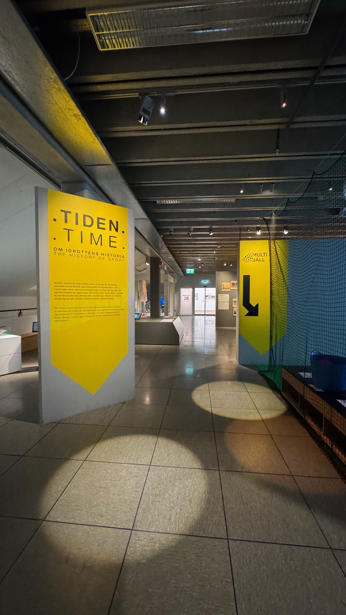 Tall yellow banners at the entrance to the exhibition Tiden, Time, at Riksidrottsmuseet.