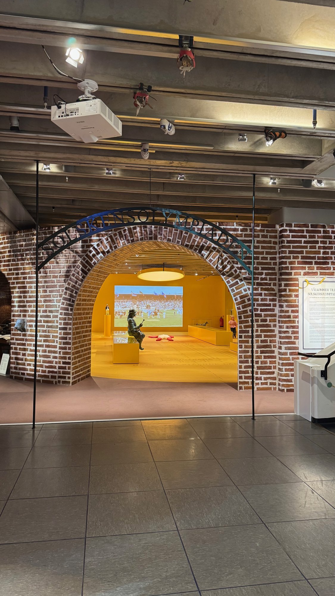 A brick arch leads to a yellow play area at Riksidrottsmuseet.
