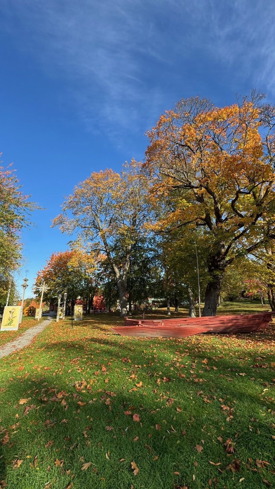 The park around Etnografiska museet with autumn trees and a green lawn.