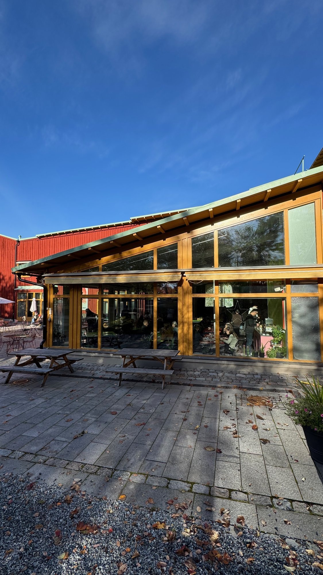 A wooden pavilion with large windows and picnic tables at Etnografiska museet.