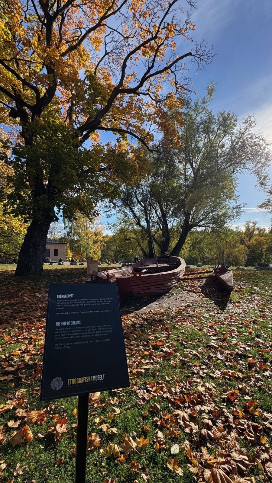 The wooden play boat Drömskeppet, the Ship of Dreams, with a sign in the autumn garden of Etnografiska museet.