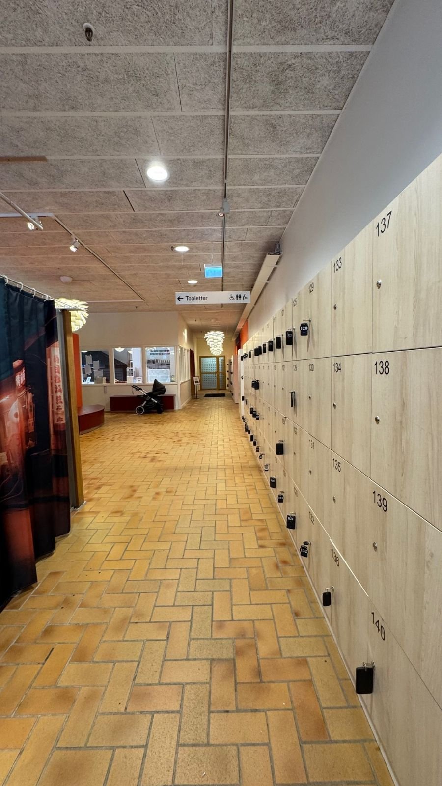 A corridor with rows of lockers and a tiled floor at Etnografiska museet.