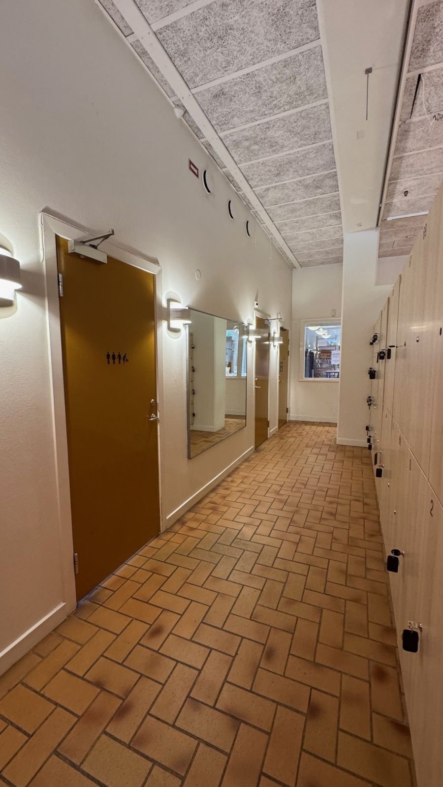 A corridor with a wooden door and lockers on the right at Etnografiska museet.