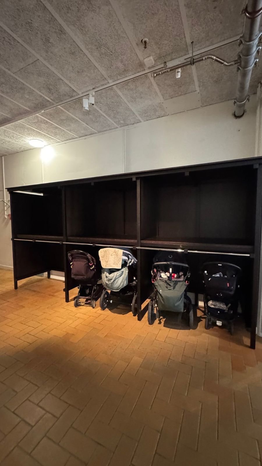 Shelves for strollers and bags under a low ceiling at Etnografiska museet.