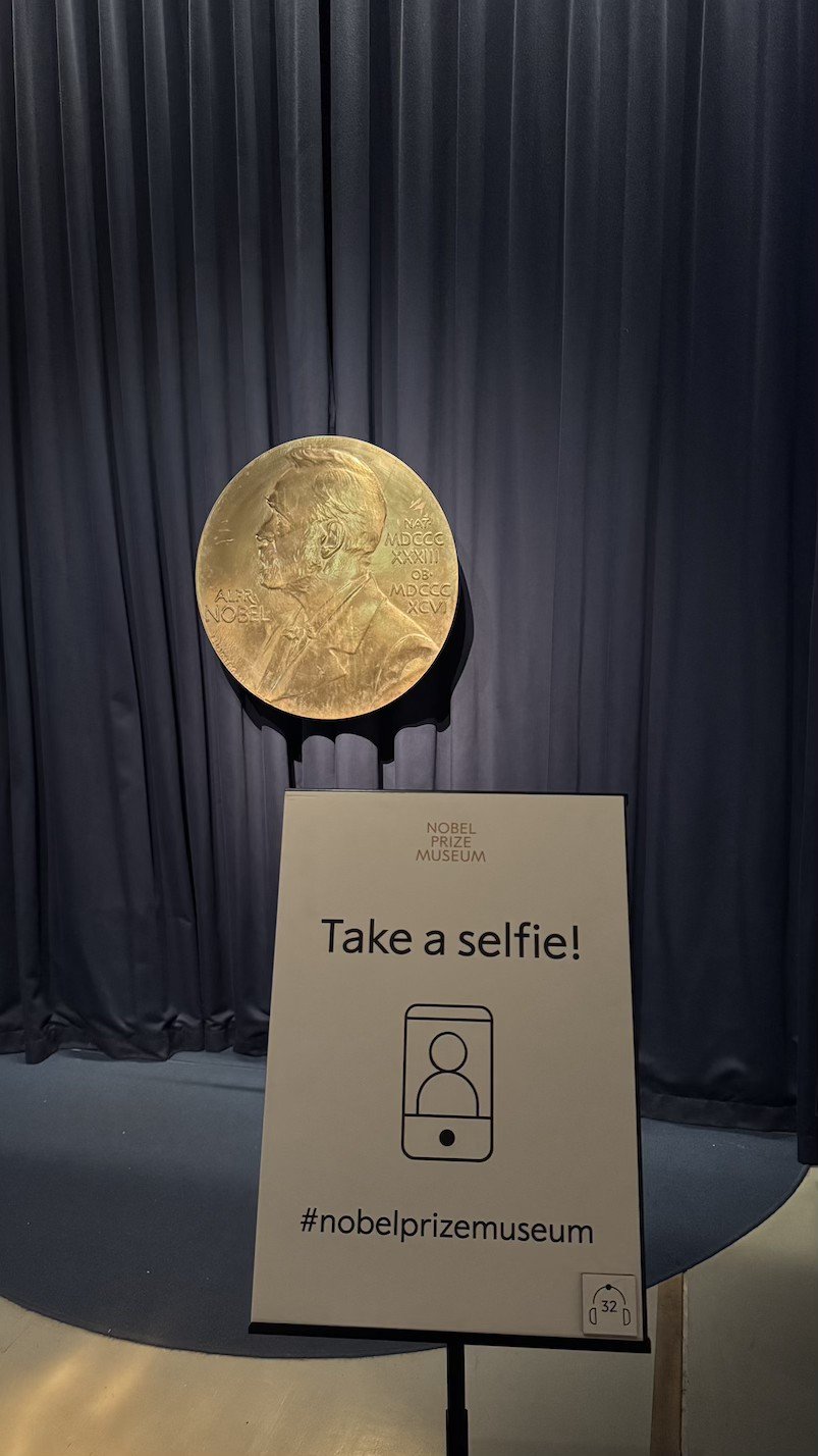 Giant gold Nobel medal replica with a 'Take a selfie!' sign at the Nobel Prize Museum.