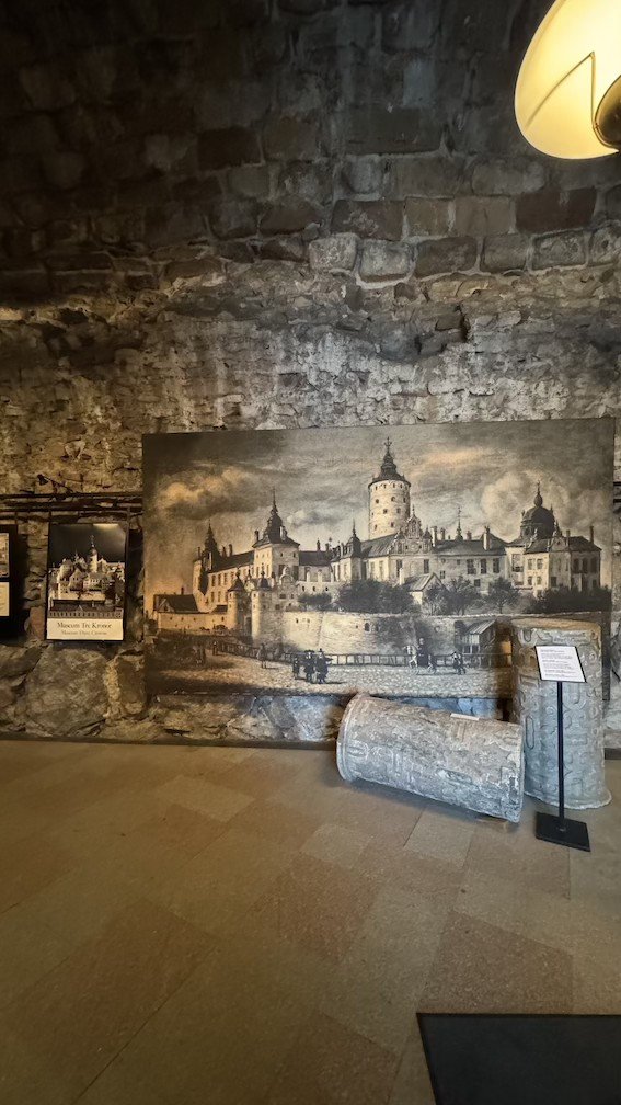 Large wall-sized reproduction of a 17th-century engraving of the Tre Kronor Palace seen from the water, displayed against the museum's stone wall.