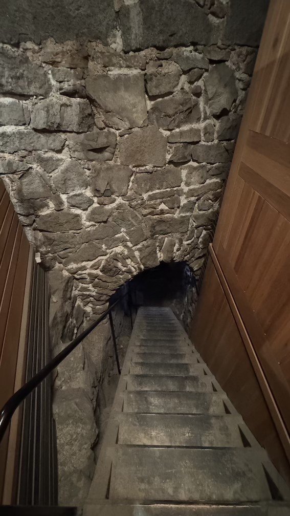 Stone spiral staircase descending into the medieval cellars of Museum Tre Kronor.