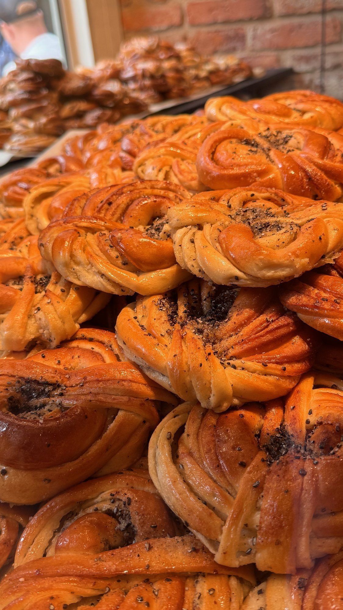 A tray of freshly baked, golden cardamom buns in a bakery.
