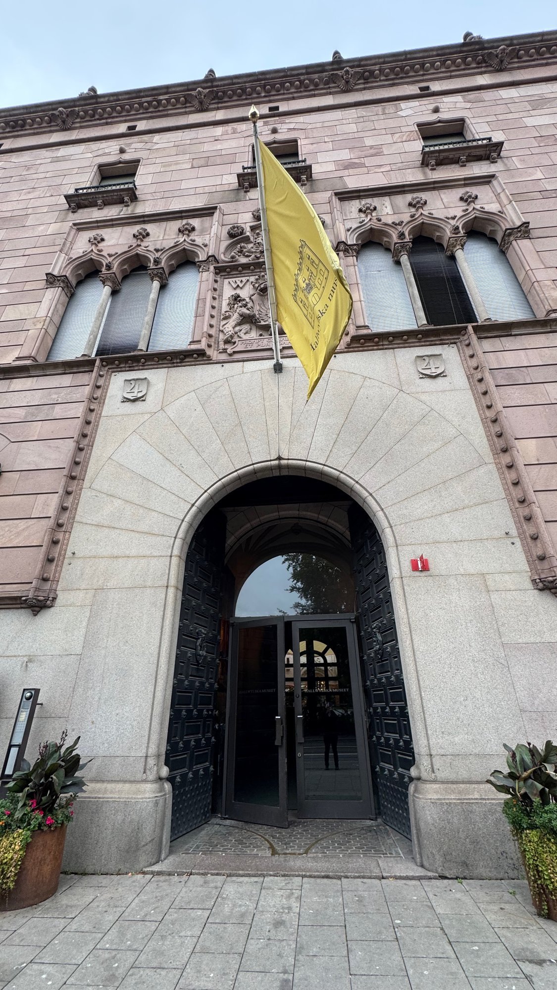 The red sandstone front of the Hallwyl Museum on Hamngatan, with a yellow flag above the arched entrance.