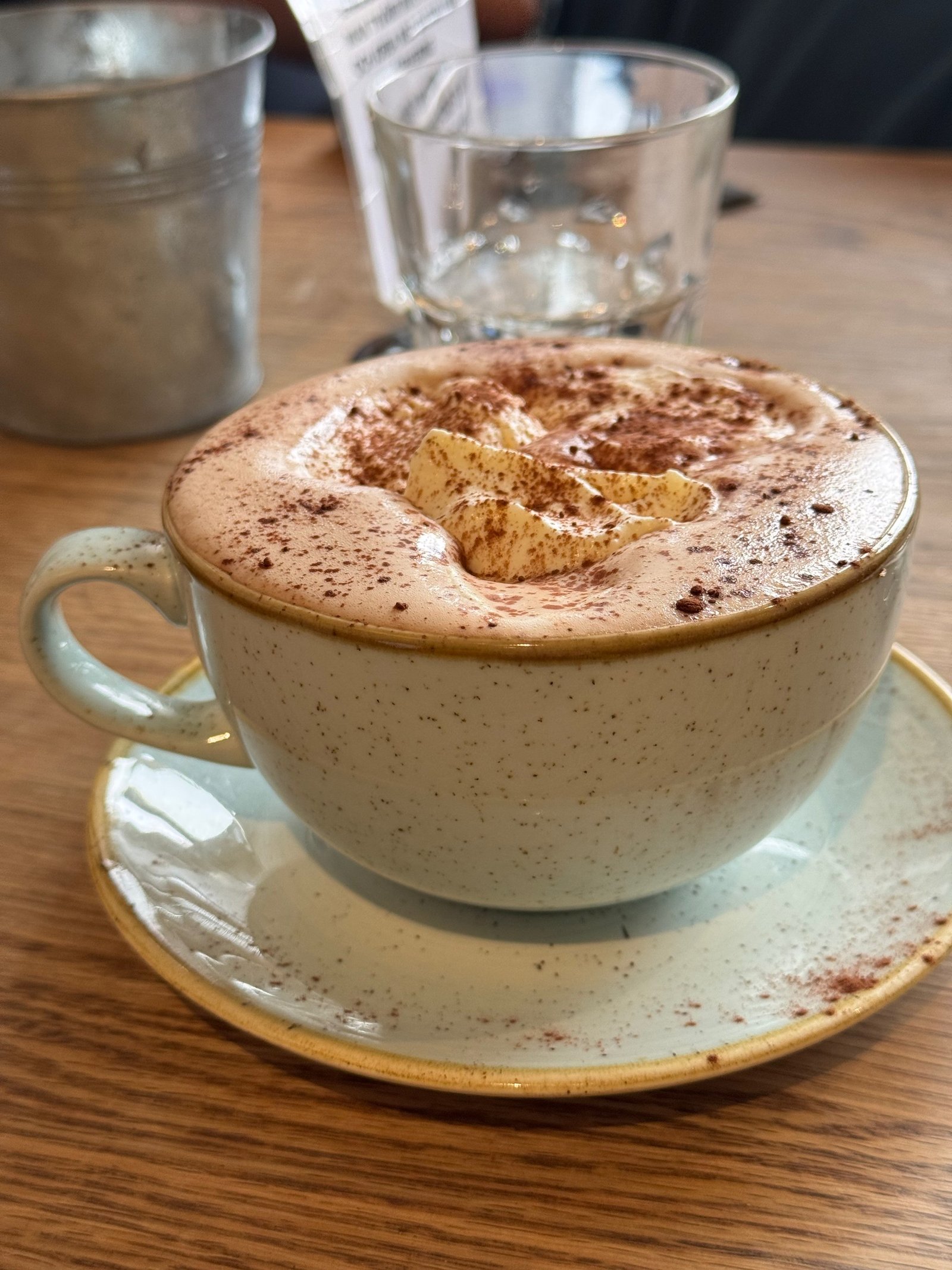 A cappuccino dusted with cinnamon is served at a caf&eacute; table during a Stockholm fika break, photographed by Zayera Khan