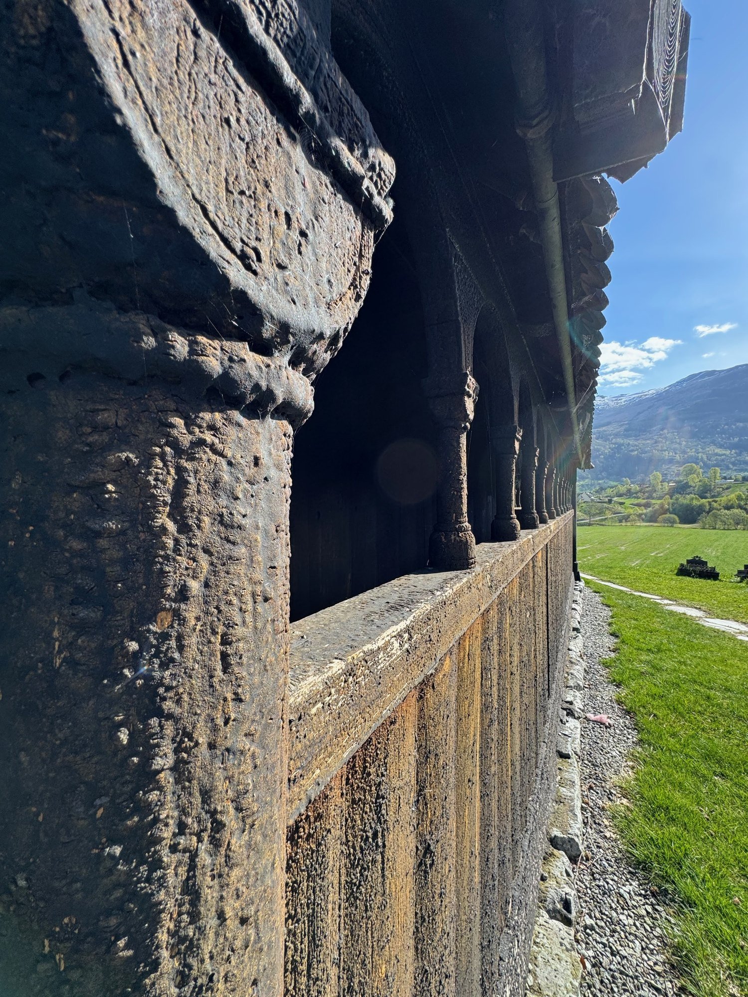 Close-up of the dark wooden outer gallery of a stave church.
