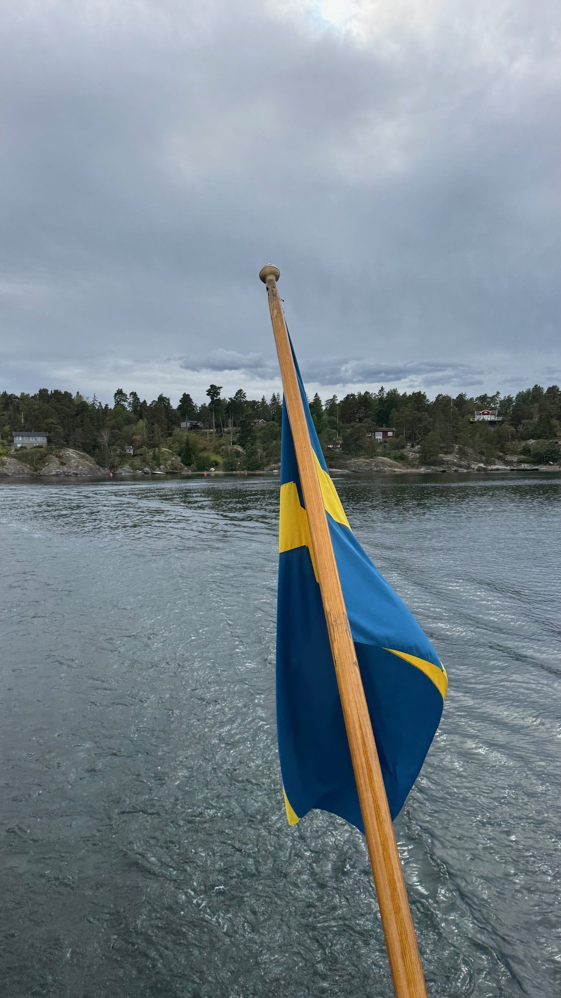 Archipelago boat with a Swedish flag at the stern and the wake behind it