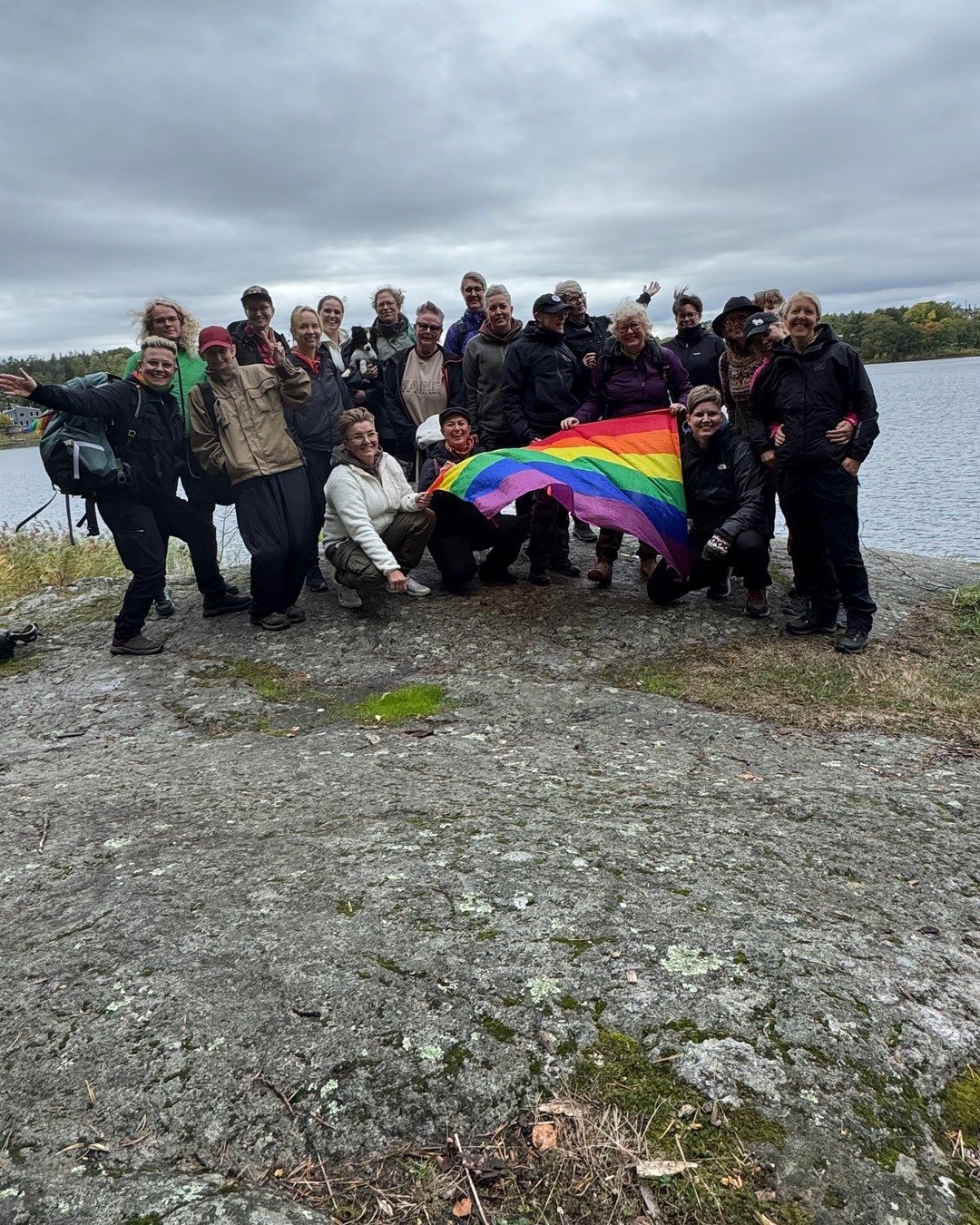 Hiking group with a Pride flag by a lake