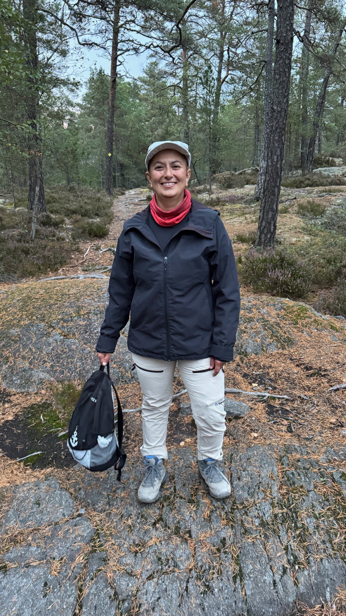Zayera Khan standing on rocks in a pine forest in Huddinge