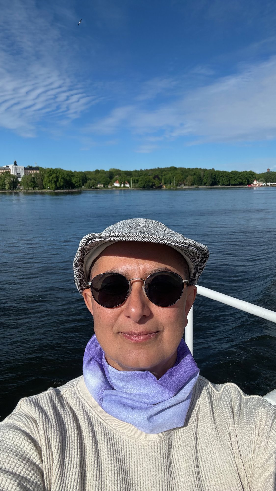 Zayera Khan in a flat cap and white scarf on a boat