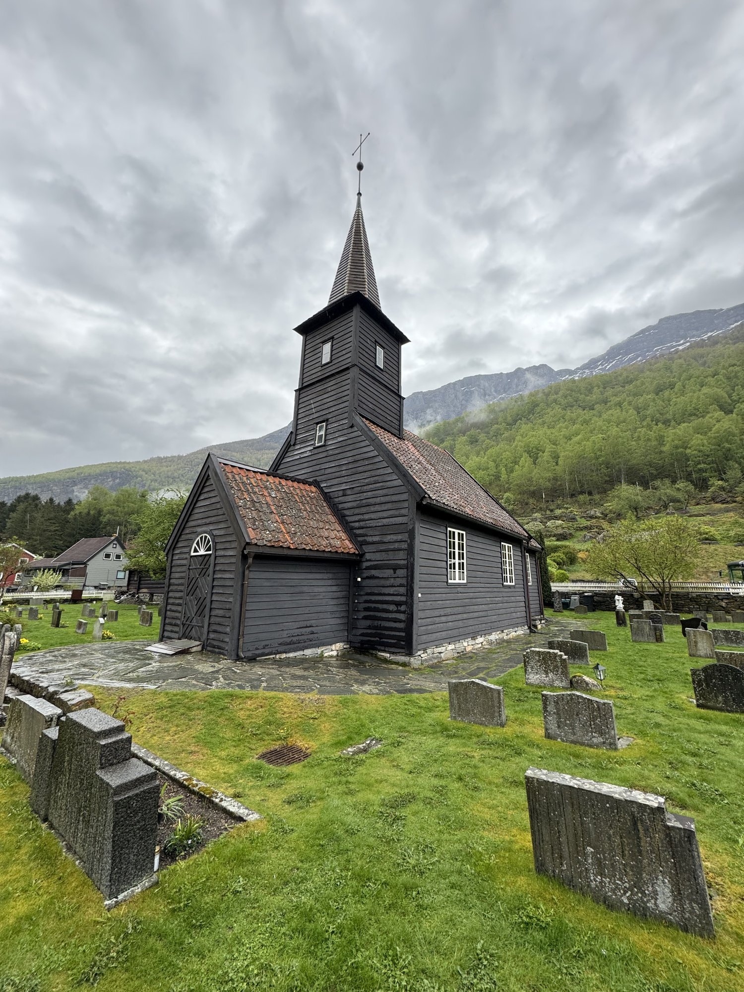 Black timber church in Flåm with the graveyard